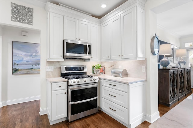 kitchen featuring appliances with stainless steel finishes, dark wood-style flooring, backsplash, and white cabinets