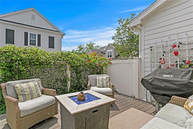 wooden deck with grilling area, fence, and an outdoor fire pit