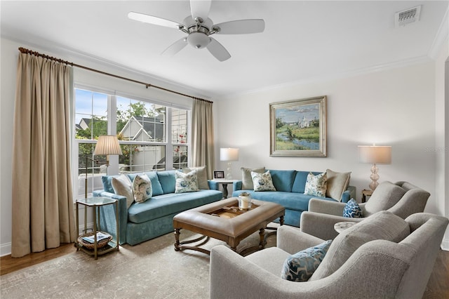 living room featuring visible vents, crown molding, a ceiling fan, and wood finished floors