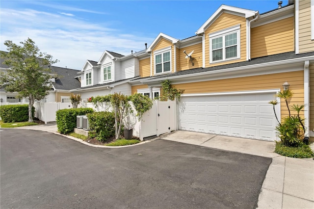 multi unit property with a garage, driveway, and fence