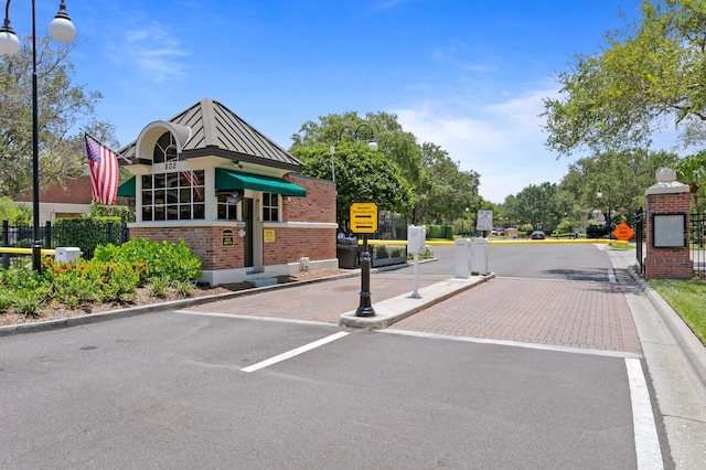 view of street with curbs, a gated entry, street lighting, and traffic signs