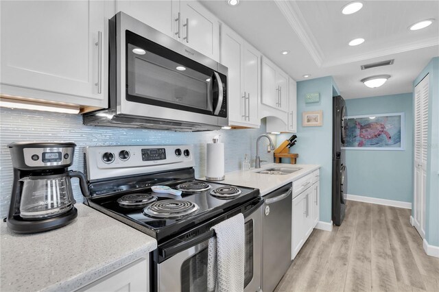 200 120th Ave W Unit 3A, Treasure Island, FL 33706 - kitchen featuring appliances with stainless steel finishes, light wood-type flooring, a sink, white cabinets, and ornamental molding