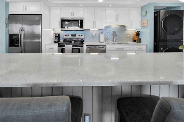 200 120th Ave W Unit 3A, Treasure Island, FL 33706 - kitchen with stainless steel appliances, estacked washer and dryer, a sink, light stone countertops, and backsplash