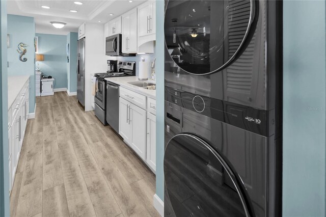 200 120th Ave W Unit 3A, Treasure Island, FL 33706 - kitchen with estacked washer and dryer, appliances with stainless steel finishes, a sink, a tray ceiling, and white cabinets