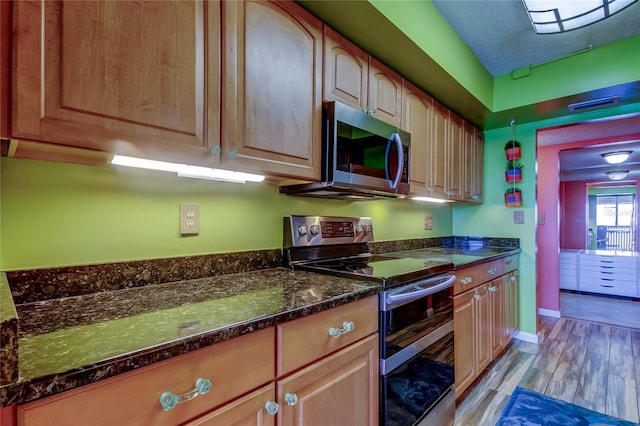 80 Rogers St Unit 2A, Clearwater, FL 33756 - kitchen with baseboards, dark stone countertops, light wood-style floors, and appliances with stainless steel finishes
