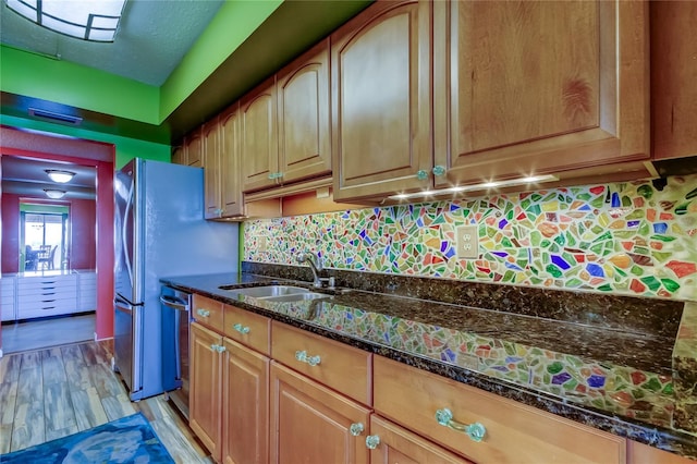 80 Rogers St Unit 2A, Clearwater, FL 33756 - kitchen featuring light wood-type flooring, stainless steel appliances, decorative backsplash, dark stone counters, and a sink