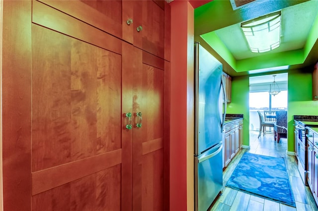 80 Rogers St Unit 2A, Clearwater, FL 33756 - kitchen featuring light wood finished floors, dark countertops, a raised ceiling, and freestanding refrigerator