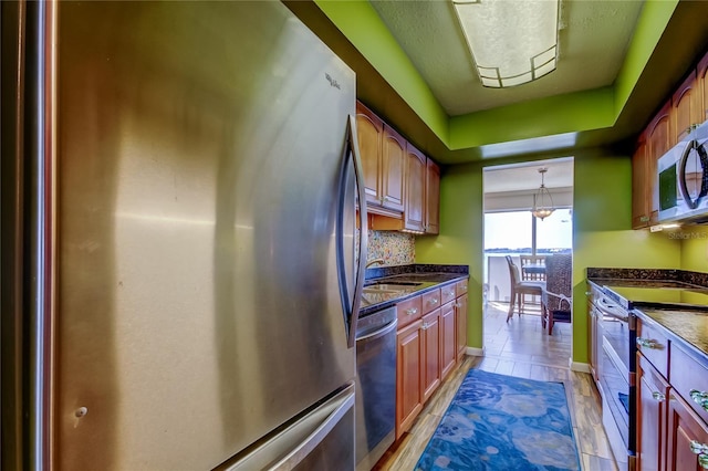 80 Rogers St Unit 2A, Clearwater, FL 33756 - kitchen featuring a sink, pendant lighting, a raised ceiling, appliances with stainless steel finishes, and decorative backsplash