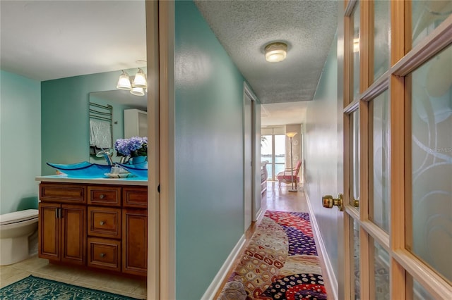 80 Rogers St Unit 2A, Clearwater, FL 33756 - hallway featuring light tile patterned floors, a notable chandelier, baseboards, and a textured ceiling