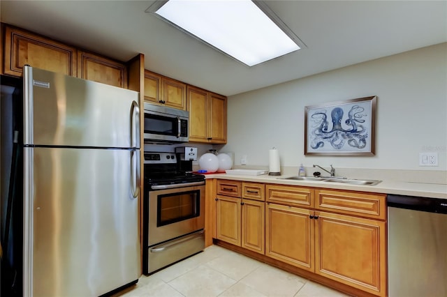 80 Rogers St Unit 2A, Clearwater, FL 33756 - kitchen with light countertops, brown cabinets, stainless steel appliances, a sink, and light tile patterned floors