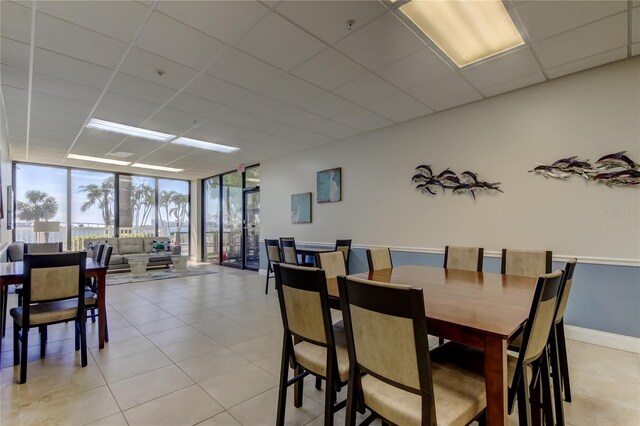 80 Rogers St Unit 2A, Clearwater, FL 33756 - dining room featuring light tile patterned flooring, baseboards, a paneled ceiling, and a wall of windows