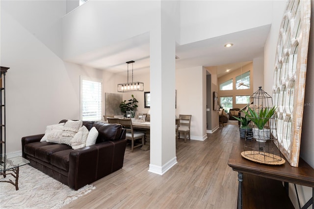 living room featuring a wealth of natural light, light wood-type flooring, and high vaulted ceiling