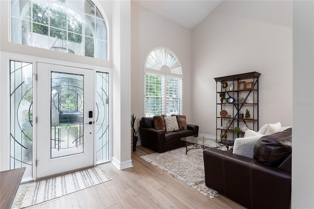 entrance foyer with baseboards, a high ceiling, and light wood-style floors