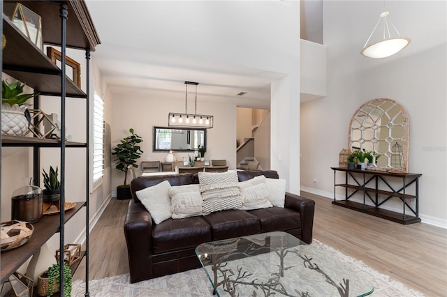 living room featuring a towering ceiling, baseboards, stairs, and wood finished floors