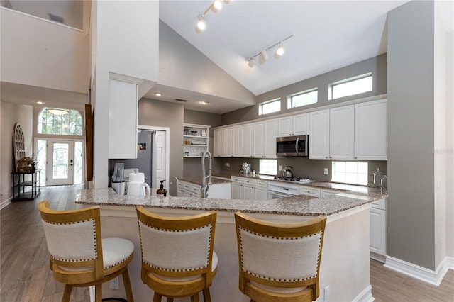 kitchen with plenty of natural light, white cabinetry, a peninsula, and stainless steel microwave