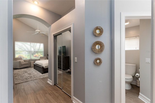 ensuite bathroom with plenty of natural light, wood finished floors, and ceiling fan