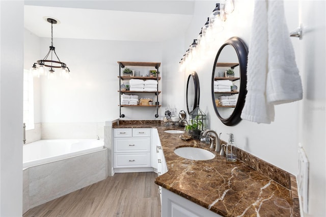 full bathroom featuring double vanity, a sink, a garden tub, and wood finished floors