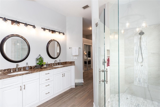 full bath with wood finished floors, a sink, tiled shower, and visible vents