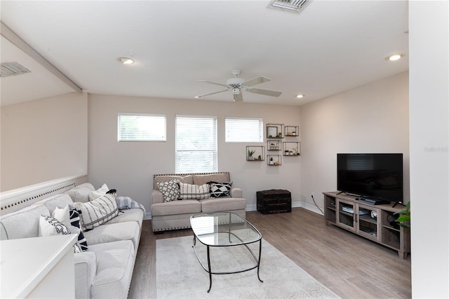living area featuring baseboards, ceiling fan, visible vents, and light wood-style floors