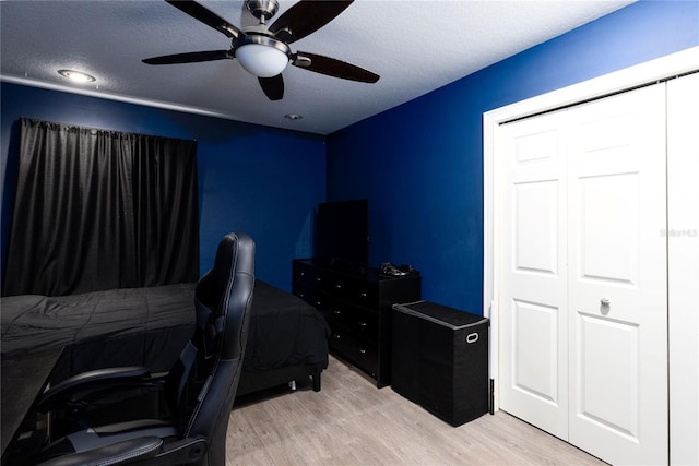 bedroom with ceiling fan, light wood finished floors, and a textured ceiling