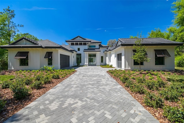 prairie-style house with an attached garage, decorative driveway, and a tile roof