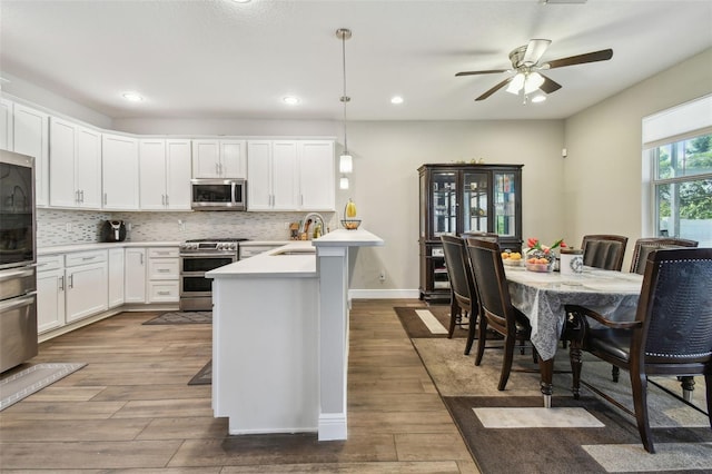4007 W Gray St, Tampa, FL 33609 - kitchen featuring a peninsula, stainless steel appliances, dark wood-style floors, and light countertops