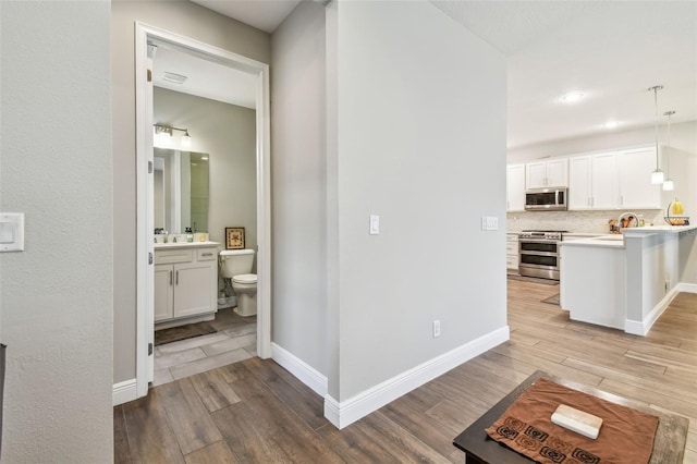 4007 W Gray St, Tampa, FL 33609 - hall featuring recessed lighting, baseboards, a sink, and light wood-type flooring