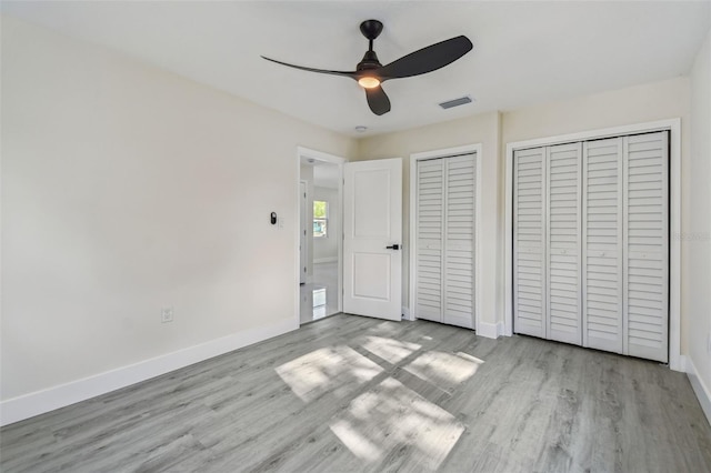 7210 8th Ave N, Saint Petersburg, FL 33710 - unfurnished bedroom featuring multiple closets, wood finished floors, and ceiling fan