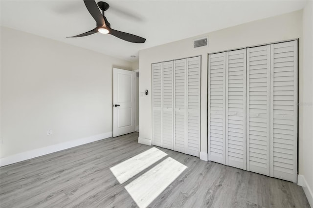 7210 8th Ave N, Saint Petersburg, FL 33710 - unfurnished bedroom featuring wood finished floors, multiple closets, and a ceiling fan