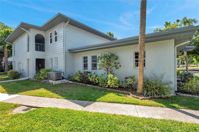 view of front of house featuring stucco siding, a front lawn, and cooling unit