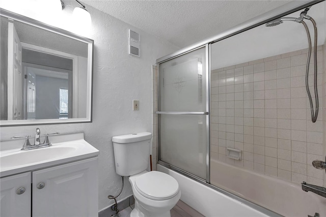 full bathroom featuring a textured wall, visible vents, toilet, vanity, and a textured ceiling
