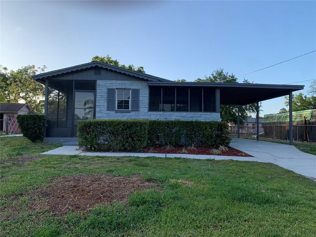 view of front of house featuring a sunroom, stone siding, and an attached carport