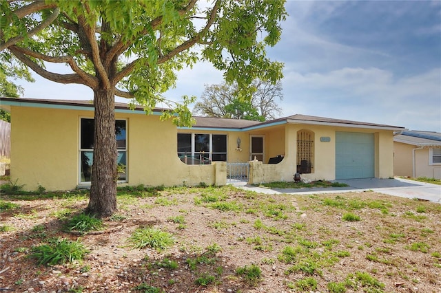 ranch-style house featuring driveway, an attached garage, fence, and stucco siding