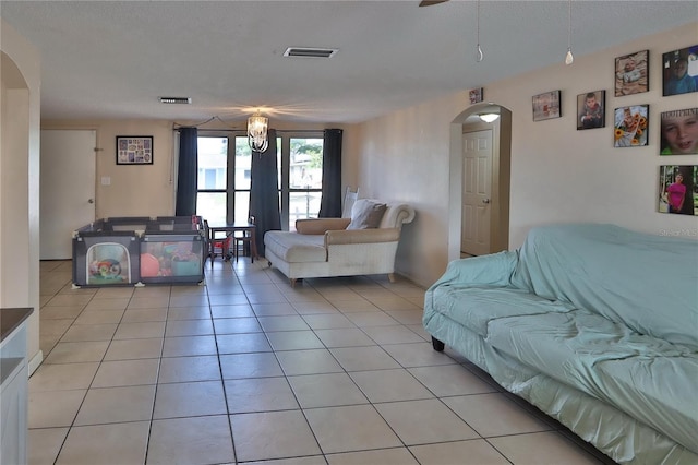 living area featuring arched walkways, ceiling fan, visible vents, and light tile patterned flooring
