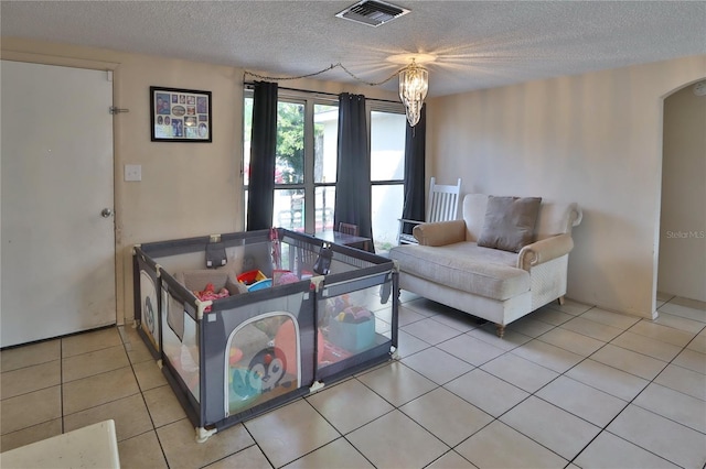 living room featuring light tile patterned flooring, a textured ceiling, visible vents, and arched walkways