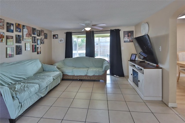 living room featuring a textured ceiling, ceiling fan, and light tile patterned floors