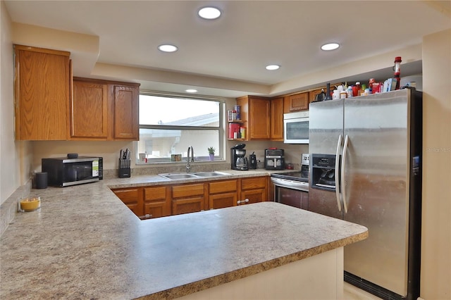 kitchen with light countertops, a sink, stainless steel appliances, and a peninsula