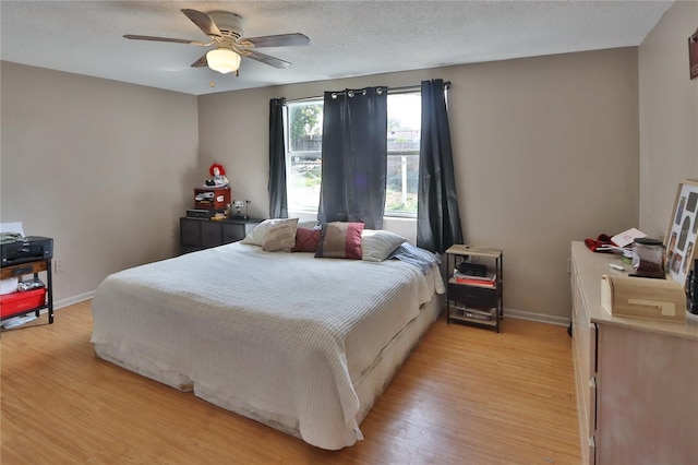 bedroom with baseboards, light wood-style flooring, ceiling fan, and a textured ceiling