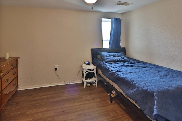 bedroom with baseboards, visible vents, and wood finished floors