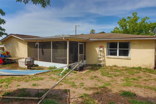 back of house with concrete block siding and a sunroom