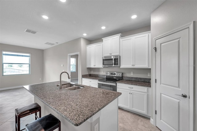 kitchen featuring visible vents, light tile patterned floors, a sink, a kitchen breakfast bar, and stainless steel appliances
