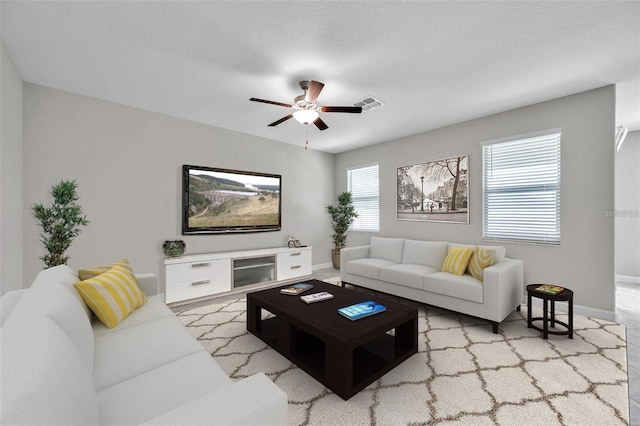 living room with visible vents, baseboards, and a ceiling fan