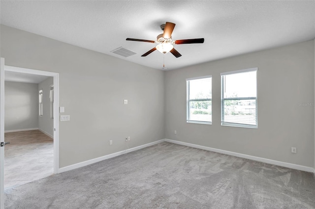 carpeted empty room with ceiling fan, baseboards, and visible vents