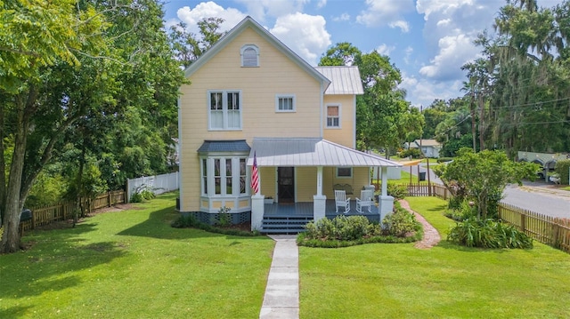 view of front of home featuring metal roof, a fenced backyard, a standing seam roof, a front lawn, and a porch