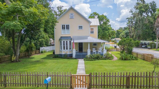 view of front of home featuring a fenced front yard, a porch, a front lawn, and metal roof