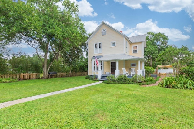 view of front of home with covered porch, metal roof, fence, and a front lawn