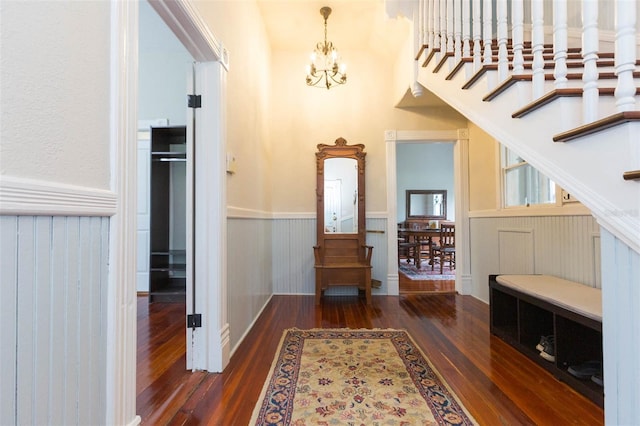 foyer entrance with a wainscoted wall, wood finished floors, and an inviting chandelier
