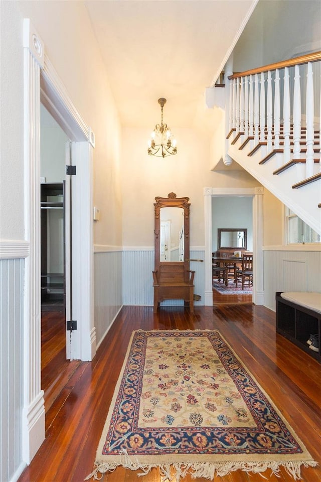 entrance foyer with hardwood / wood-style floors, wainscoting, and a chandelier