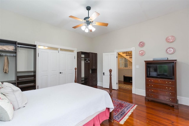 bedroom featuring two closets, baseboards, ceiling fan, and wood finished floors