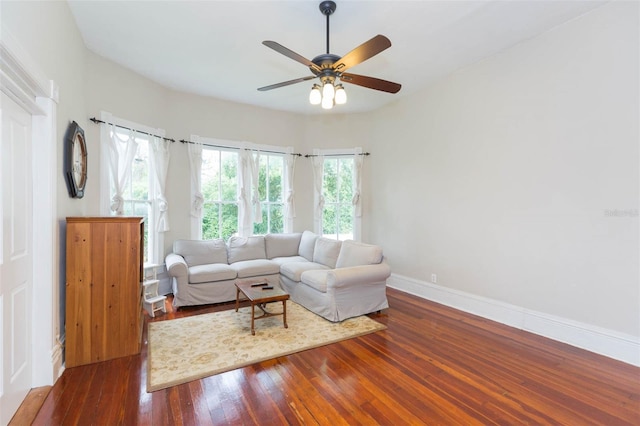 living area featuring baseboards, a wealth of natural light, hardwood / wood-style flooring, and a ceiling fan